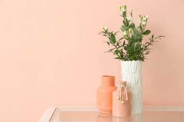 Renk duvarının yanındaki masada güzel çiçekli vazolar.