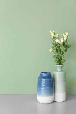 Renk duvarının yanındaki masada güzel çiçekli vazolar.