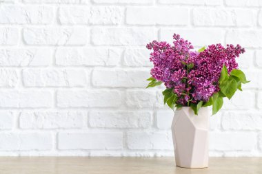 Beyaz tuğla duvarın yanındaki masada güzel çiçekli vazo.