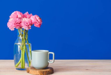 Güzel çiçekli vazo ve renkli duvarın yanındaki masada fincan.