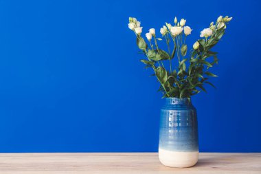 Renk duvarının yanındaki masada güzel çiçekli vazo.