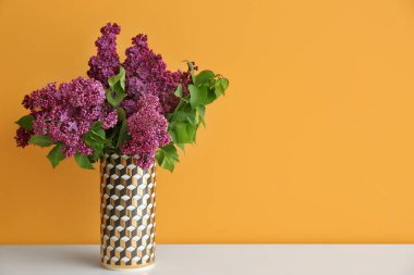 Renk duvarının yanındaki masada güzel çiçekli vazo.