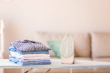 Odadaki ütü masasında bir yığın temiz giysi var.