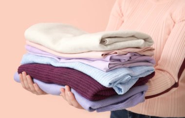 Renkli arka planda temiz kıyafet yığını olan kadın, yakın plan.