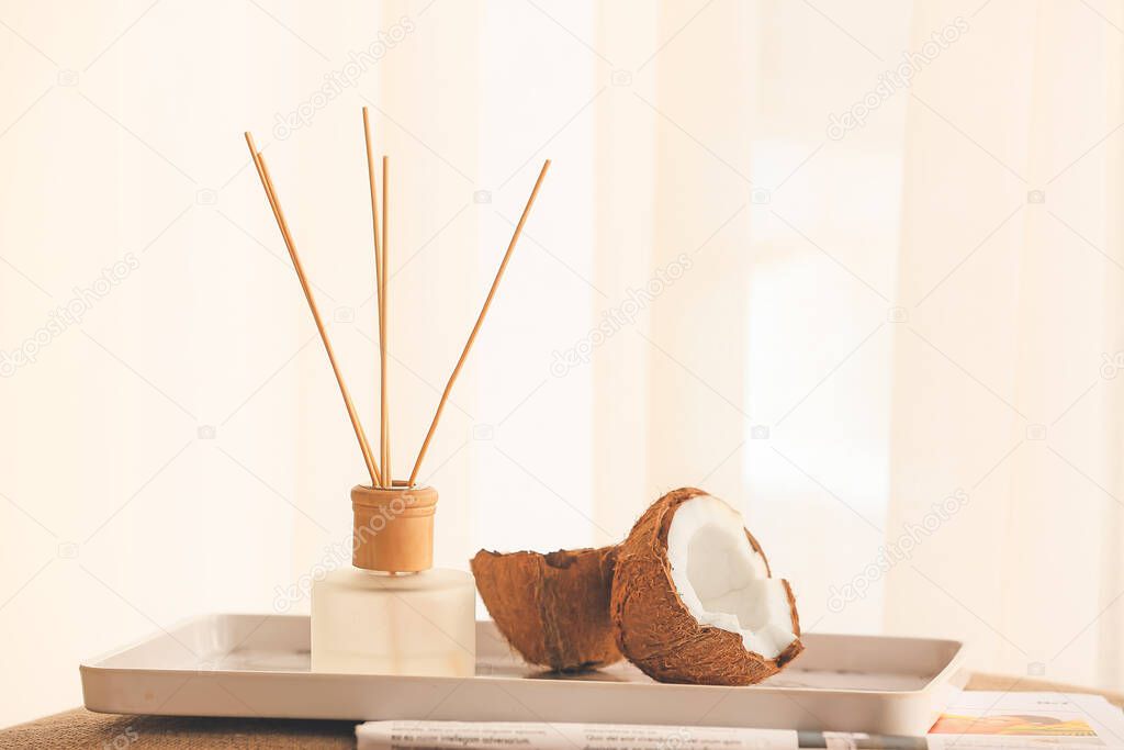 Reed diffuser and coconut on table in room