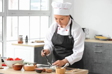 Güzel Asyalı aşçı mutfakta yemek yapıyor.