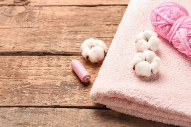 Pamuk çiçekleri, iplikler ve ahşap arka planda yumuşak havlu.