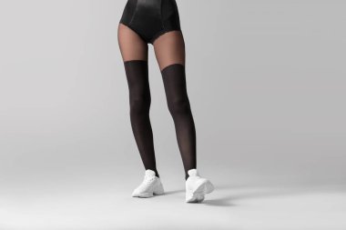 Gri arka planda tayt giymiş güzel bir kadın.