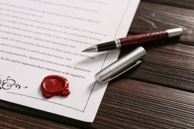 Ahşap arka planda kalemle yapılan evlilik sözleşmesi.