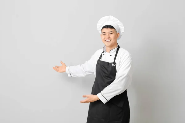 Guapo Asiático Chef Mostrando Algo Gris Fondo —  Fotos de Stock