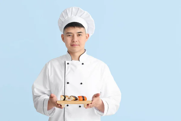 Fešák Asijský Kuchař Sushi Rolls Barevném Pozadí — Stock fotografie