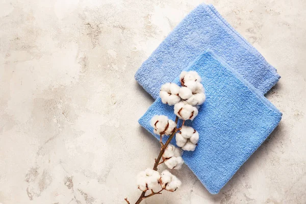 Cotton flowers and soft towels on light background