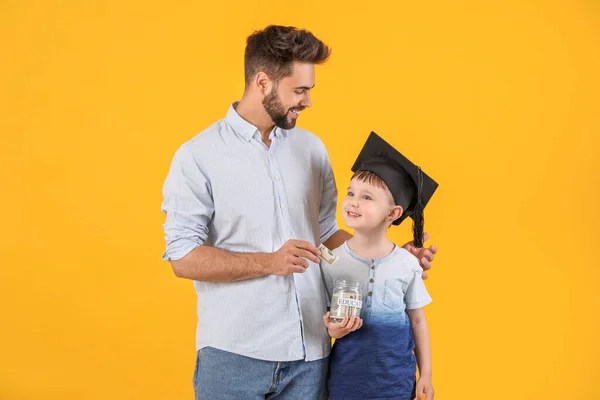 Liten Pojke Och Far Med Pengar Burk Färg Bakgrund Begreppet — Stockfoto