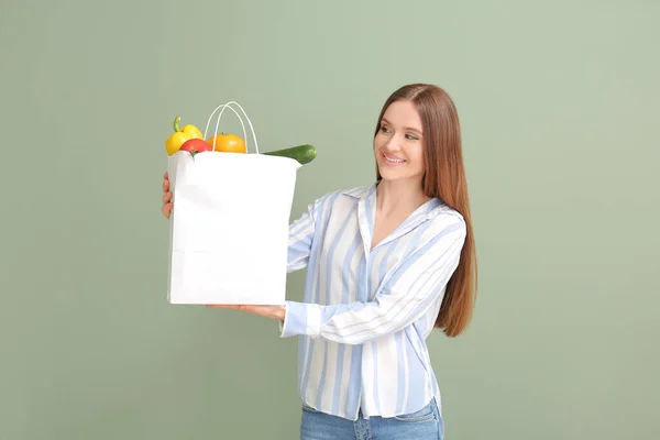 色の背景に食べ物と袋を保持若い女性 — ストック写真