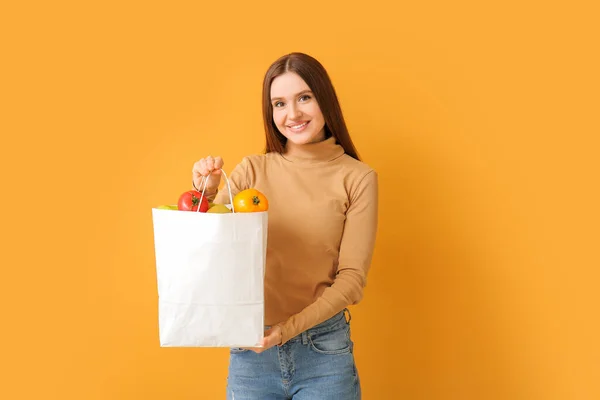 Junge Frau Hält Tasche Mit Lebensmitteln Auf Farbigem Hintergrund — Stockfoto