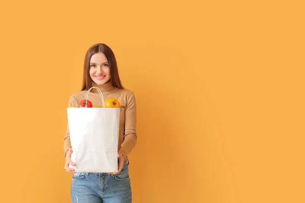 Junge Frau Hält Tasche Mit Lebensmitteln Auf Farbigem Hintergrund — Stockfoto