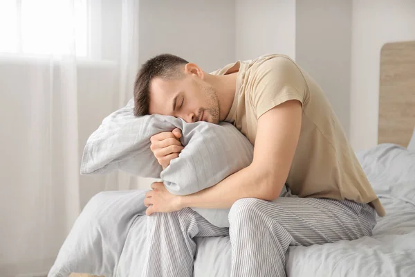 Young man suffering from sleep deprivation in bedroom