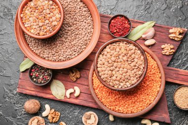 Esmer arka planda baharatlı farklı çiğ mercimek.