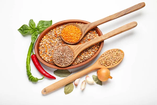 Raw lentils and spices on white background