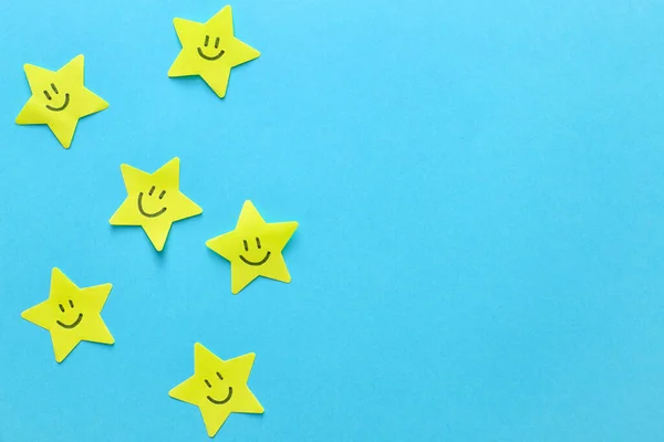 Gwiazdy Papieru Narysowanymi Szczęśliwymi Twarzami Tle Koloru — Zdjęcie stockowe