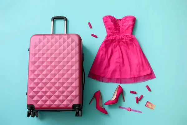 Packed suitcase and accessories on color background