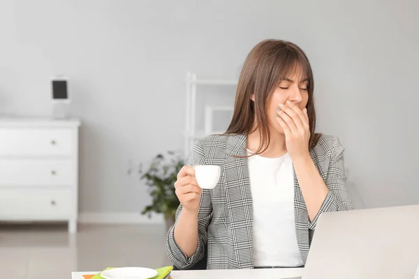 Young woman suffering from sleep deprivation in office