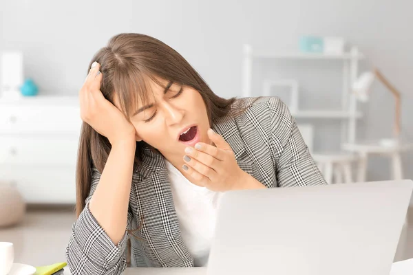 Young woman suffering from sleep deprivation in office