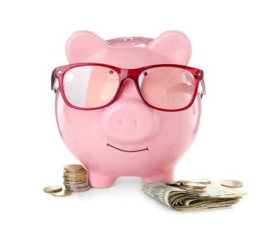 Gözlüklü ve beyaz arka planda parası olan bir kumbara.