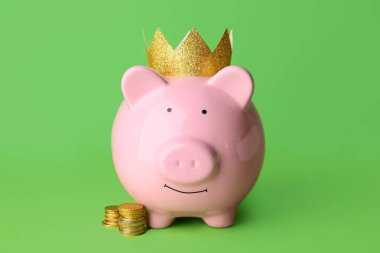 Taçlı domuz kumbarası ve renkli arka planda para