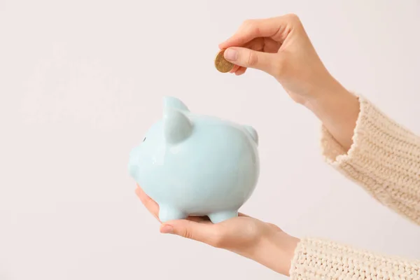 Woman Putting Money Piggy Bank Light Background — Stock Photo, Image