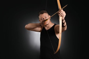 Arkaplanda yayı olan yakışıklı bir erkek okçu.