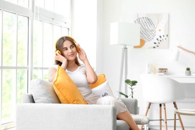 Evde müzik dinleyen güzel genç bir kadın.