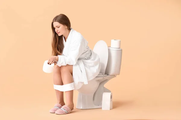 Jovem Mulher Sentada Vaso Sanitário Contra Fundo Cor — Fotografia de Stock