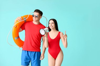 Beach rescuers with lifebuoy and megaphone on color background clipart