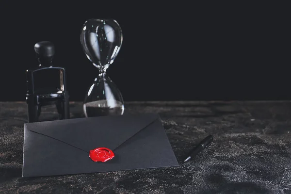 Envelope with notary public wax seal, stamp and hourglass on table