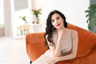 Evin içinde şık takılar takan güzel genç bir kadın.