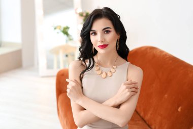 Evin içinde şık takılar takan güzel genç bir kadın.