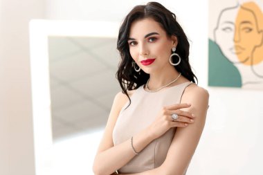 Evin içinde şık takılar takan güzel genç bir kadın.