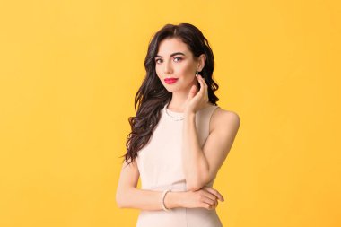 Renkli arka planda şık takılar takan güzel genç bir kadın.