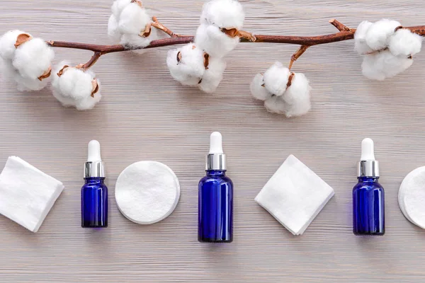 Bottles of cottonseed oil with cosmetic pads on table