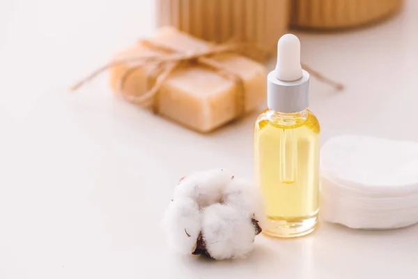 Bottle of cottonseed oil with cosmetic pads on table