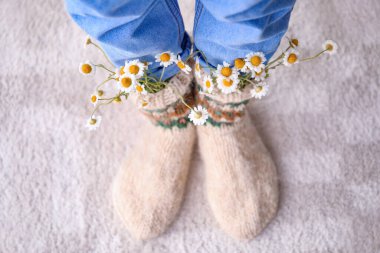 Evde papatyalı örgü çorap giyen bir kadın var.