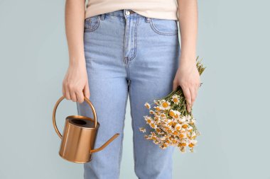 Sulama kutusu ve gri arka planda papatya çayı olan bir kadın.