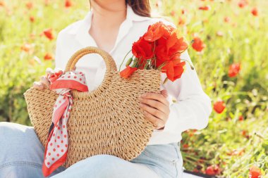 Tarlada haşhaş çiçekleri olan güzel genç bir kadın.