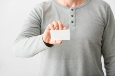 Açık arkaplanda boş kartviziti olan bir adam.