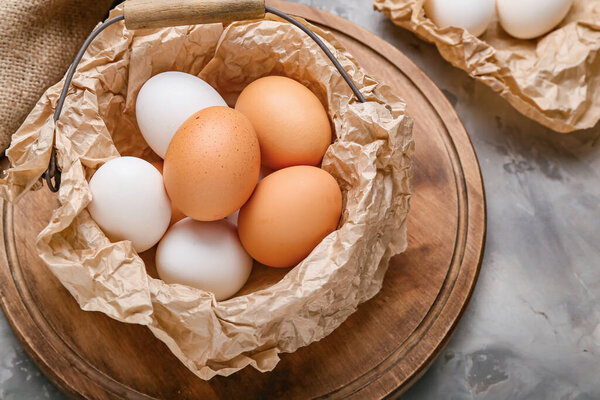 Basket with chicken eggs on grey background