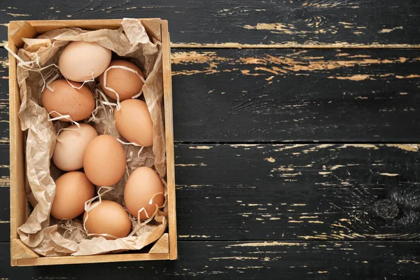 Box with chicken eggs on wooden background