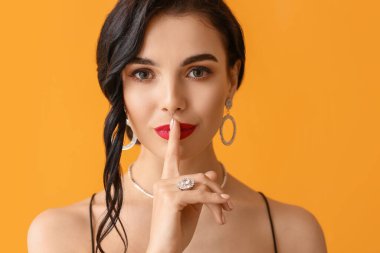 Güzel genç bir kadın, arka planda sessizlik jesti yapıyor.