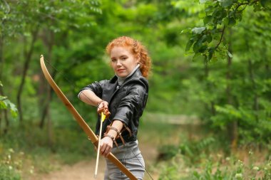 Dışarıda okçuluk yapan genç bir bayan.