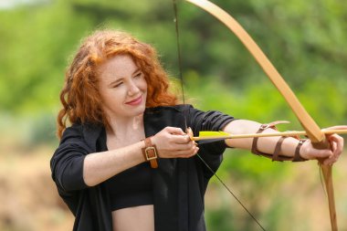 Dışarıda okçuluk yapan genç bir bayan.